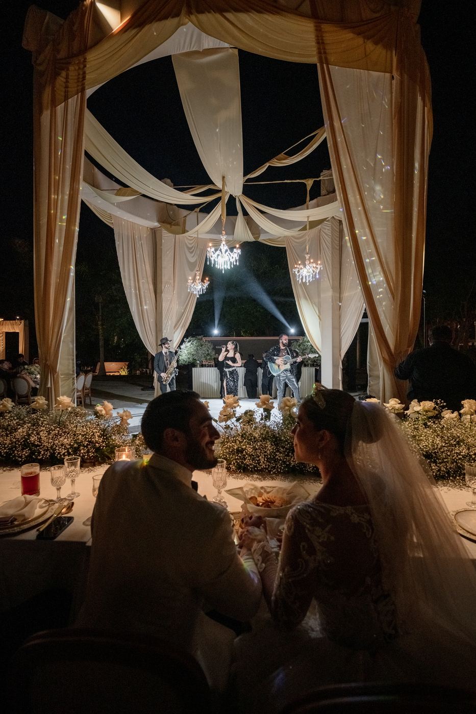La pareja en su mesa durante la recepción bajo cortinas iluminadas