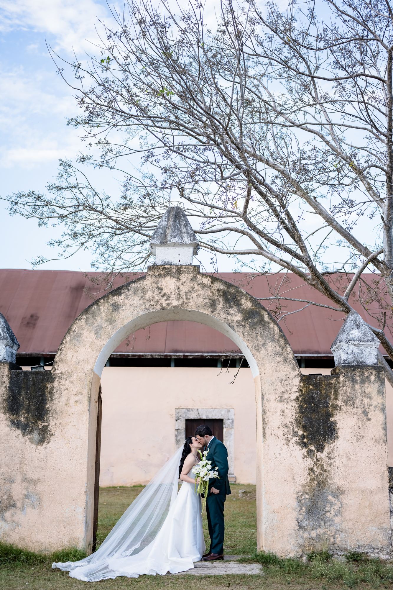 Pareja besándose bajo un arco de piedra de una hacienda yucateca