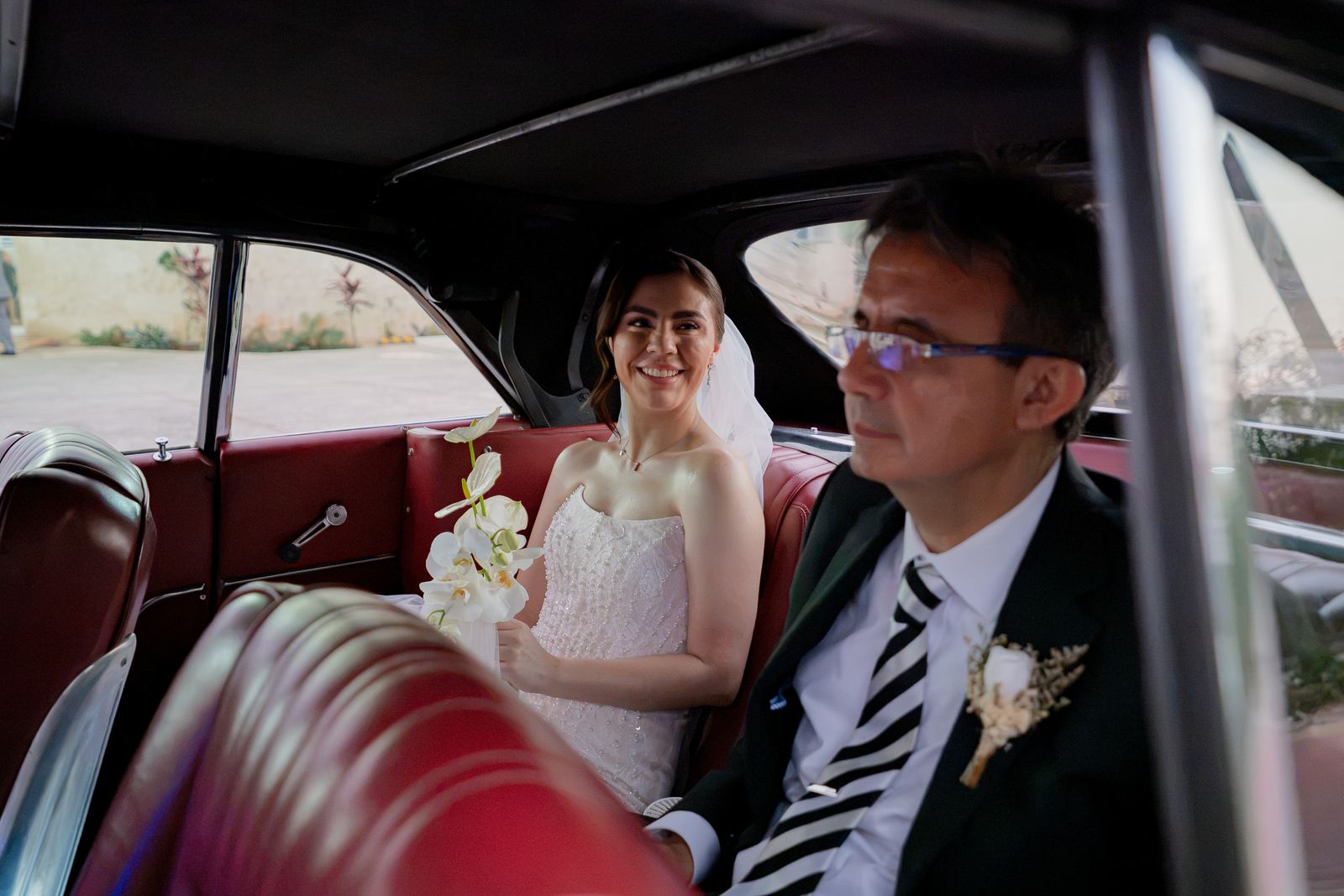 Los novios dentro de un auto clásico de interiores rojos
