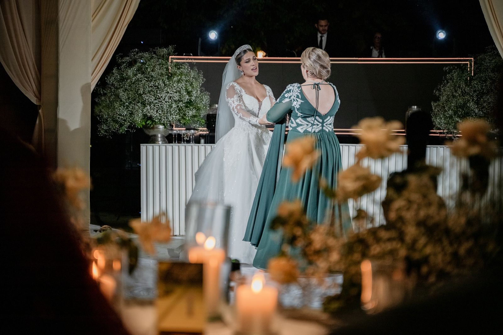 La novia y su mamá bailando, vistas entre velas y flores