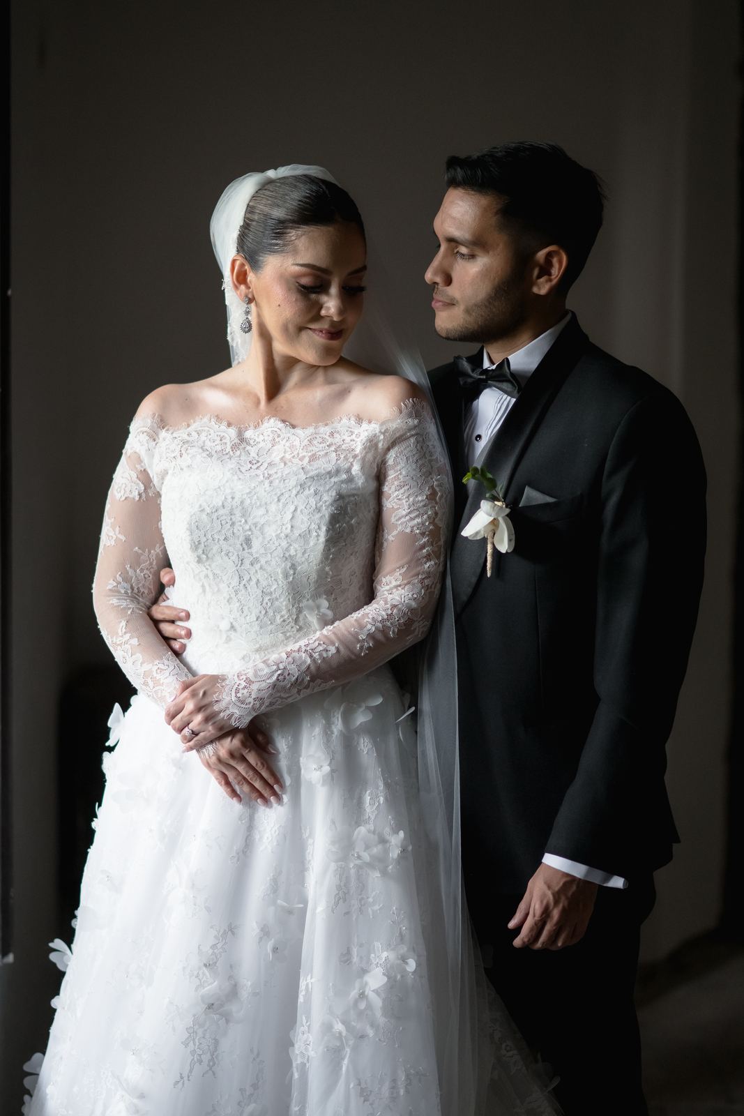 Retrato de los novios con luz de ventana en un salón oscuro
