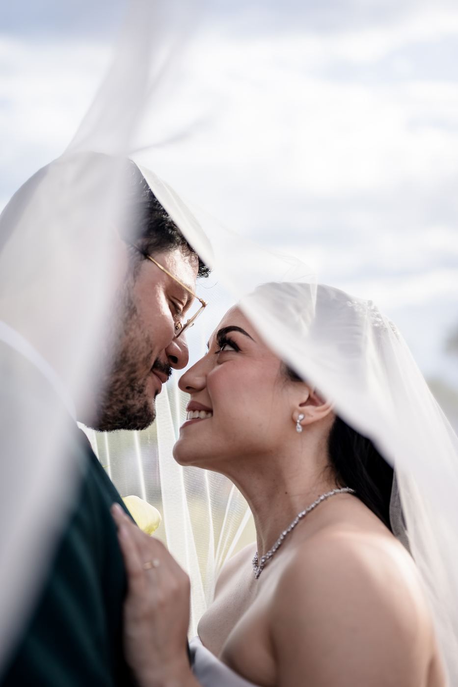 Los novios frente a frente bajo el velo, a punto de besarse